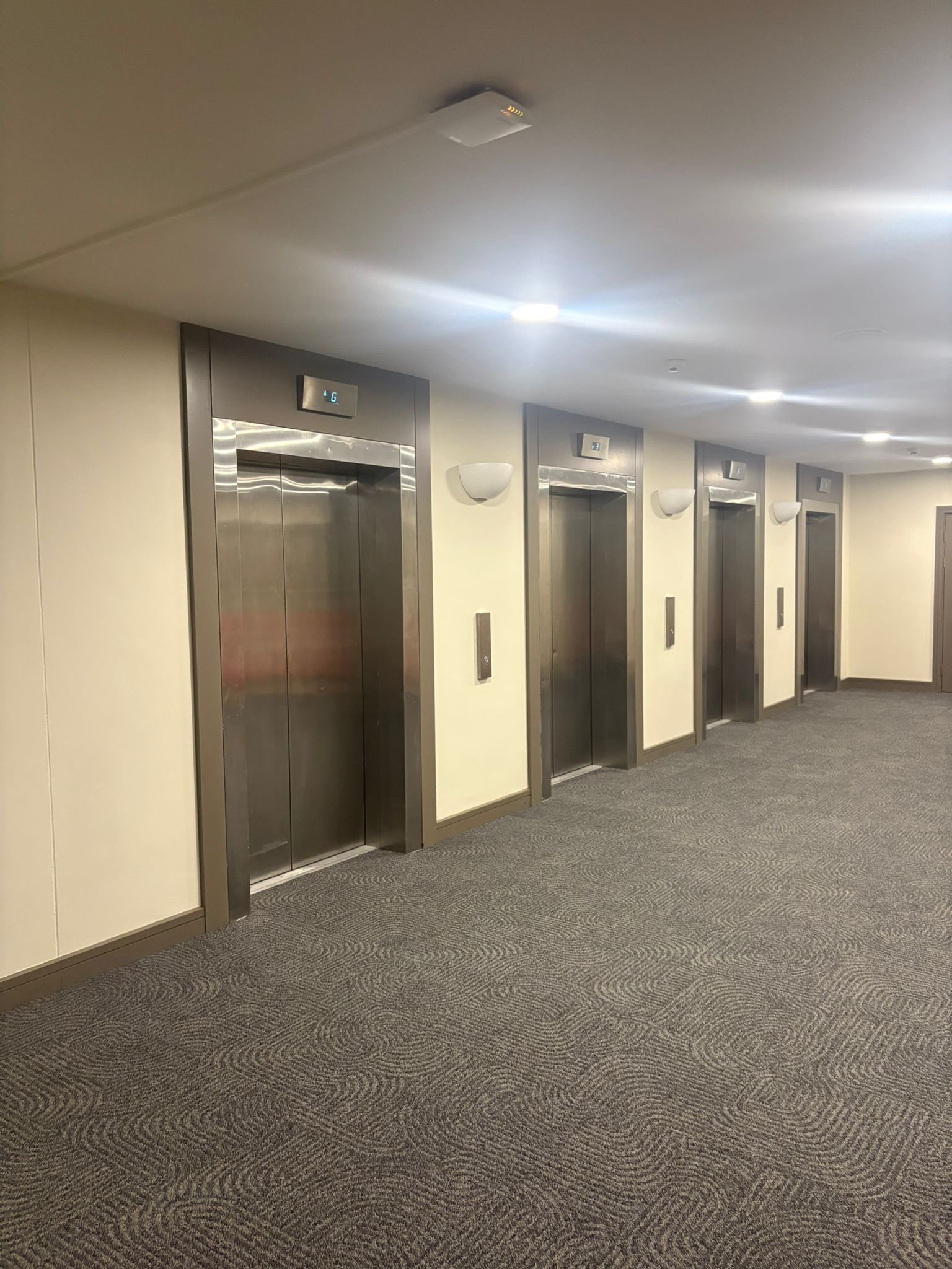 Commercial corridor with cream walls and lift bank decorated